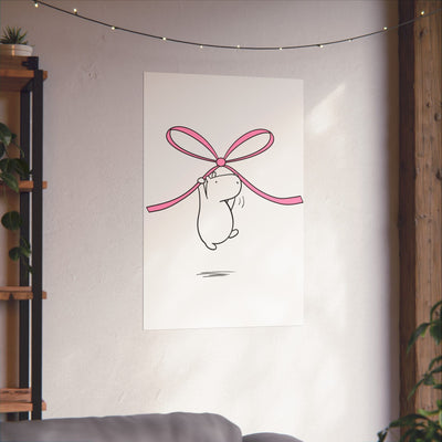 Capy Life minimalist wall art print featuring a cute capybara hanging from a pink bow on a white wall in a room.