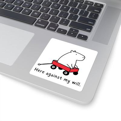 Capy Life vinyl sticker featuring a capybara in a red wagon with the text Here against my will on a laptop