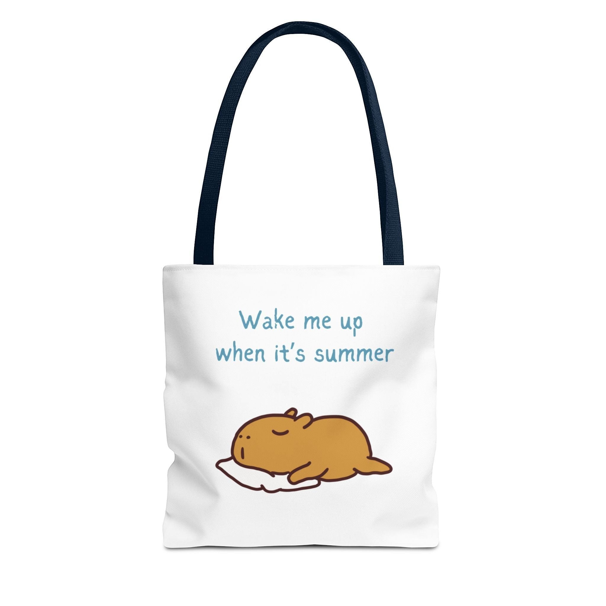 Capy Life white canvas tote bag featuring a cute illustration of a sleepy capybara and the text Wake me up when it's summer with dark blue handles.