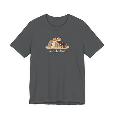 Capy Life dark grey t-shirt featuring a hand-drawn capybara checking Santa's naughty or nice list while he naps.