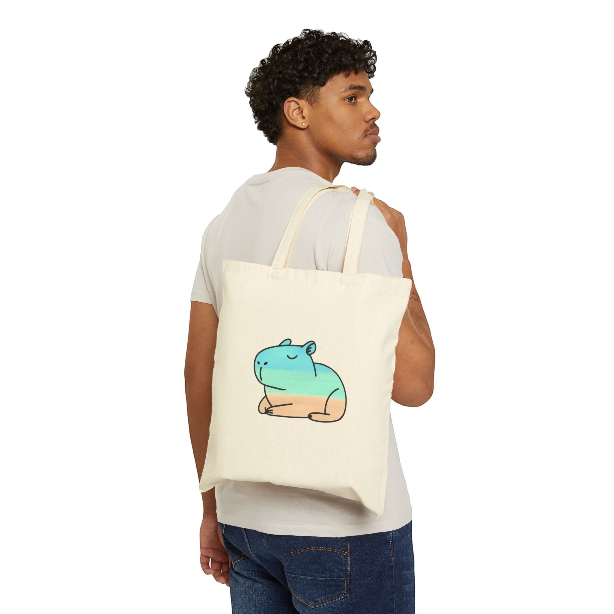 Capy Life coastal capybara canvas tote bag in natural cotton worn over the shoulder by a man in a white t-shirt.