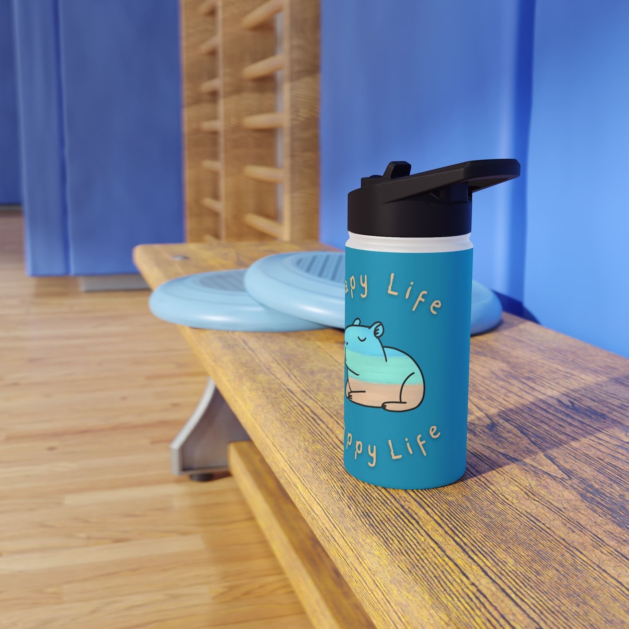 Capy Life 12oz stainless steel water bottle with a coastal capybara design on a wooden bench in a gym setting.