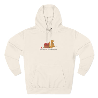 Capy Life cream fleece hoodie featuring a hand-drawn capybara eating a cider donut next to a basket of red apples.