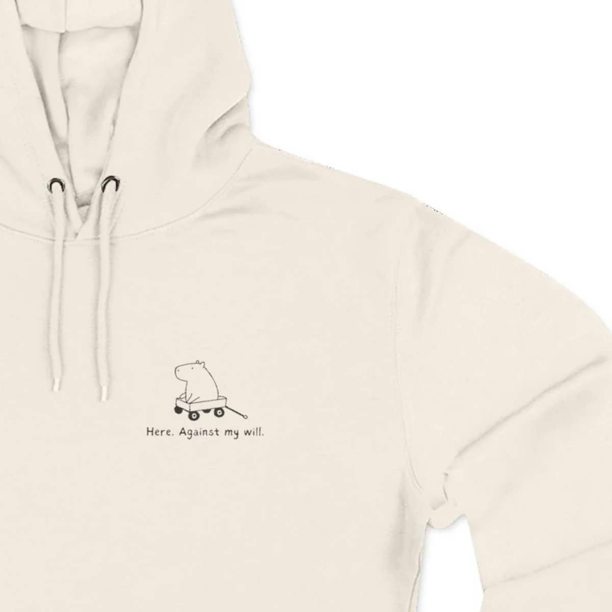 Capy Life cream-colored unisex hoodie featuring a minimalist embroidered capybara in a wagon with Here Against My Will