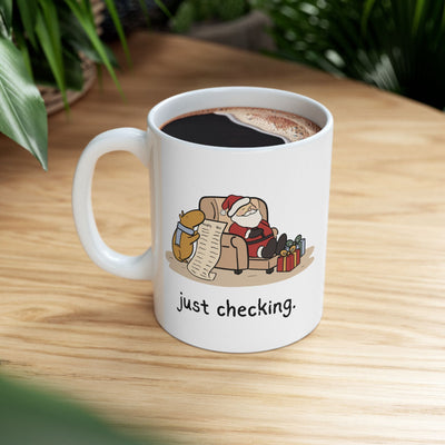 Capy Life white ceramic mug featuring a capybara in a blue scarf checking Santa's naughty or nice list.