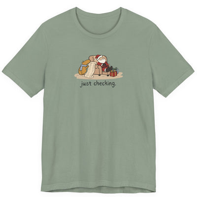 Capy Life sage green t-shirt featuring a hand-drawn capybara checking Santa's naughty or nice list while he naps.