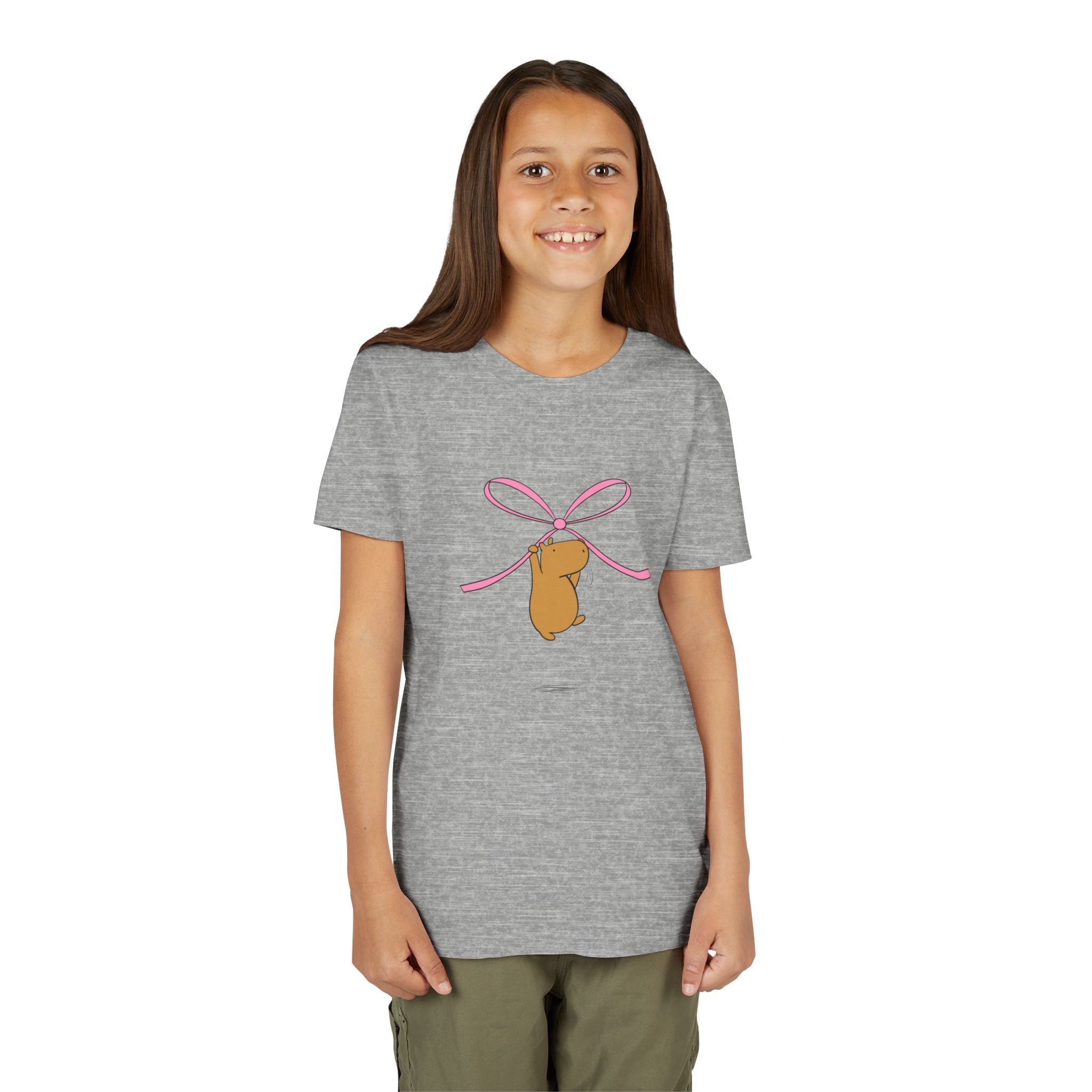 A young girl wearing a Capy Life heather grey cotton t-shirt featuring a cute capybara hanging from a pink bow.