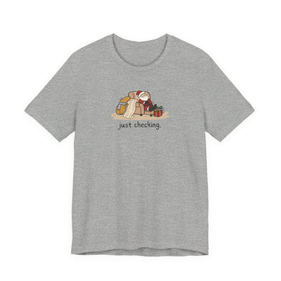 Capy Life grey t-shirt featuring a hand-drawn capybara checking Santa's naughty or nice list while he naps.