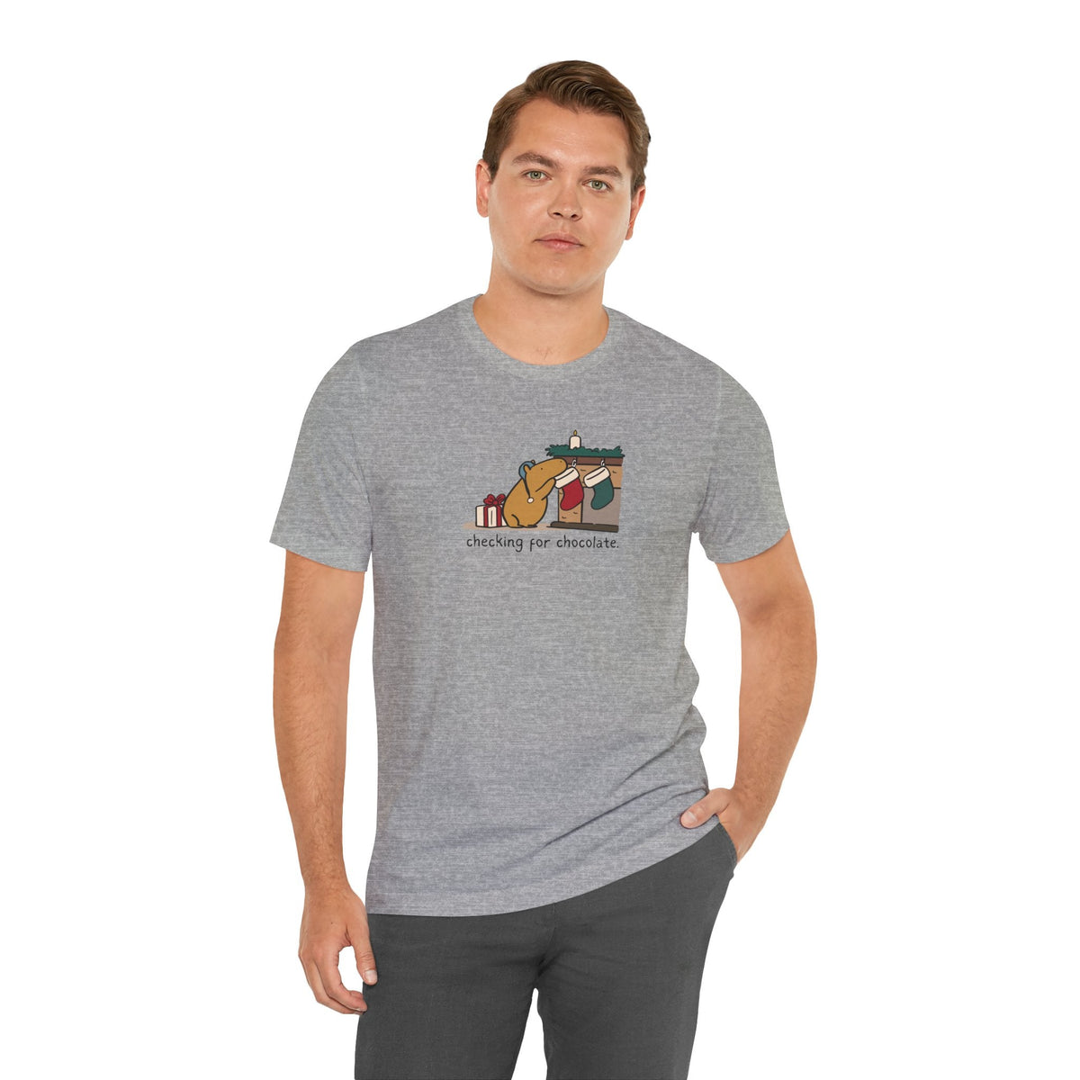 Man wearing a grey Capy Life softstyle t-shirt featuring a capybara checking a Christmas stocking for chocolate.