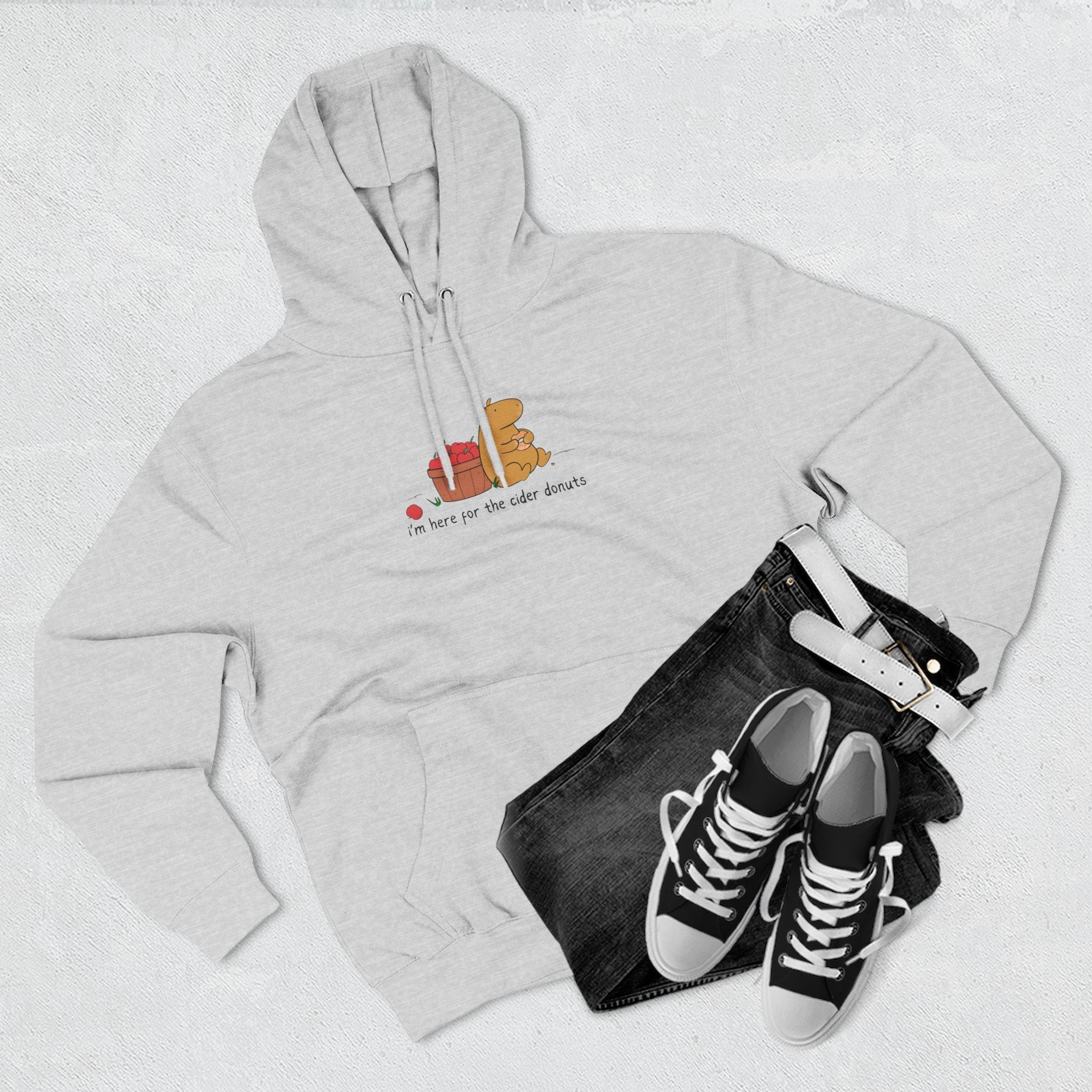 Capy Life grey fleece hoodie with a cute capybara eating a cider donut, paired with black jeans and sneakers.
