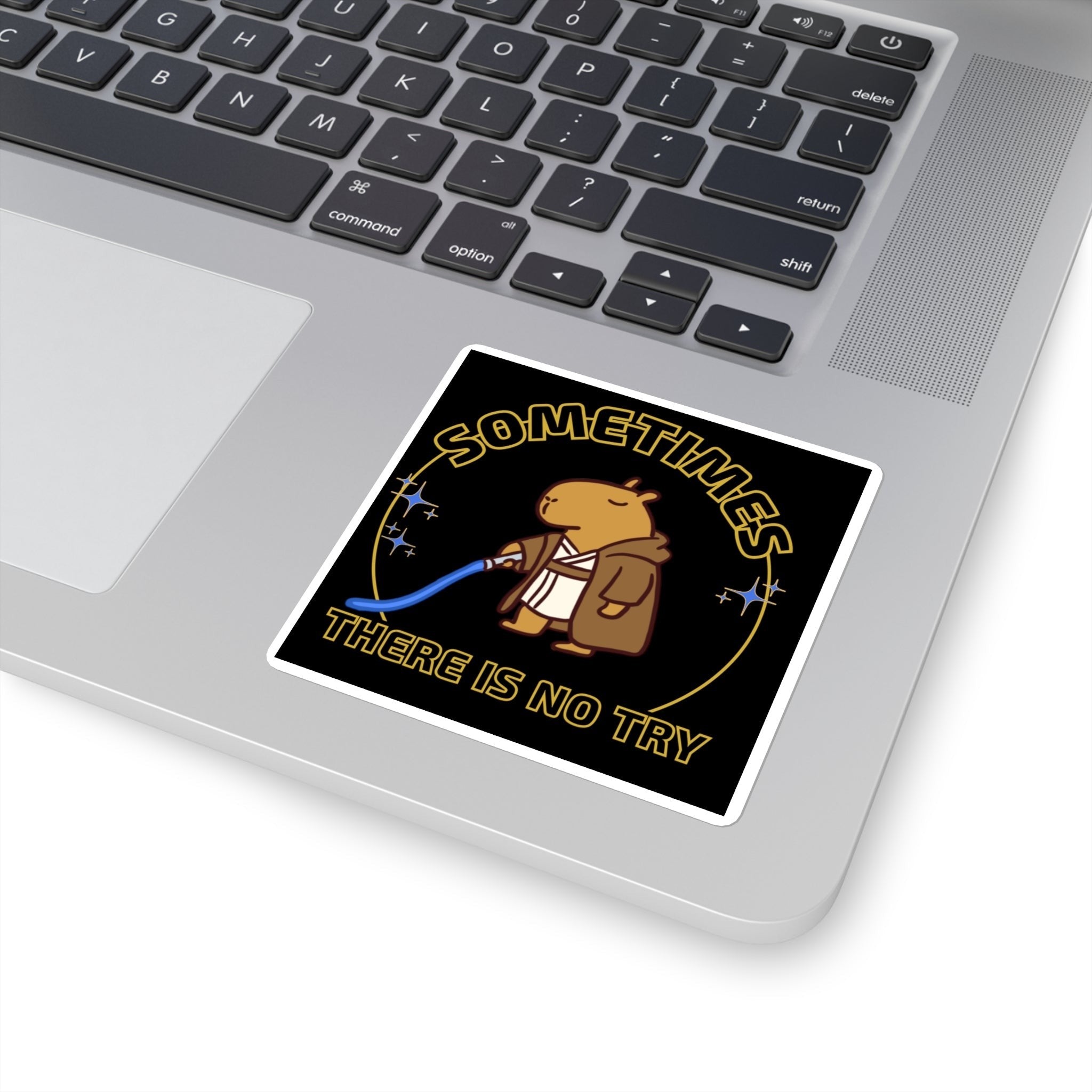 Capy Life sticker on a laptop featuring a capybara in a Jedi robe holding a blue lightsaber with gold text.