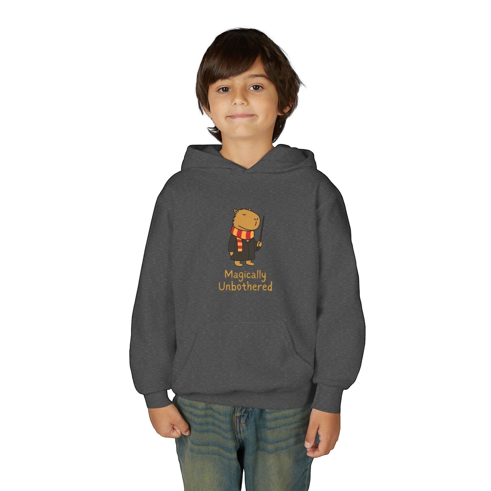 Capy Life kids dark grey hoodie featuring a cute capybara wizard illustration with the text Magically Unbothered.