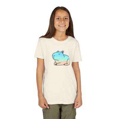A girl wearing a Capy Life kids coastal capybara graphic t-shirt in cream with a blue and tan hand-painted capybara.