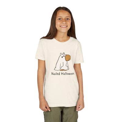 A young girl wearing a cream Capy Life kids t-shirt featuring a cute capybara in a ghost costume and Nailed Halloween