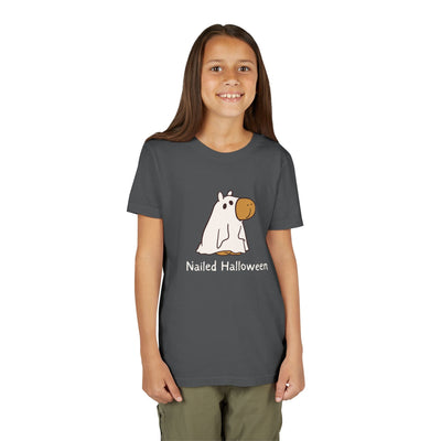 A young girl wearing a dark grey Capy Life kids t-shirt featuring a cute capybara in a ghost costume with Nailed Halloween text.