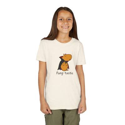 A young girl wearing a Capy Life cream-colored t-shirt featuring a cute capybara in a vampire cape and fangs.