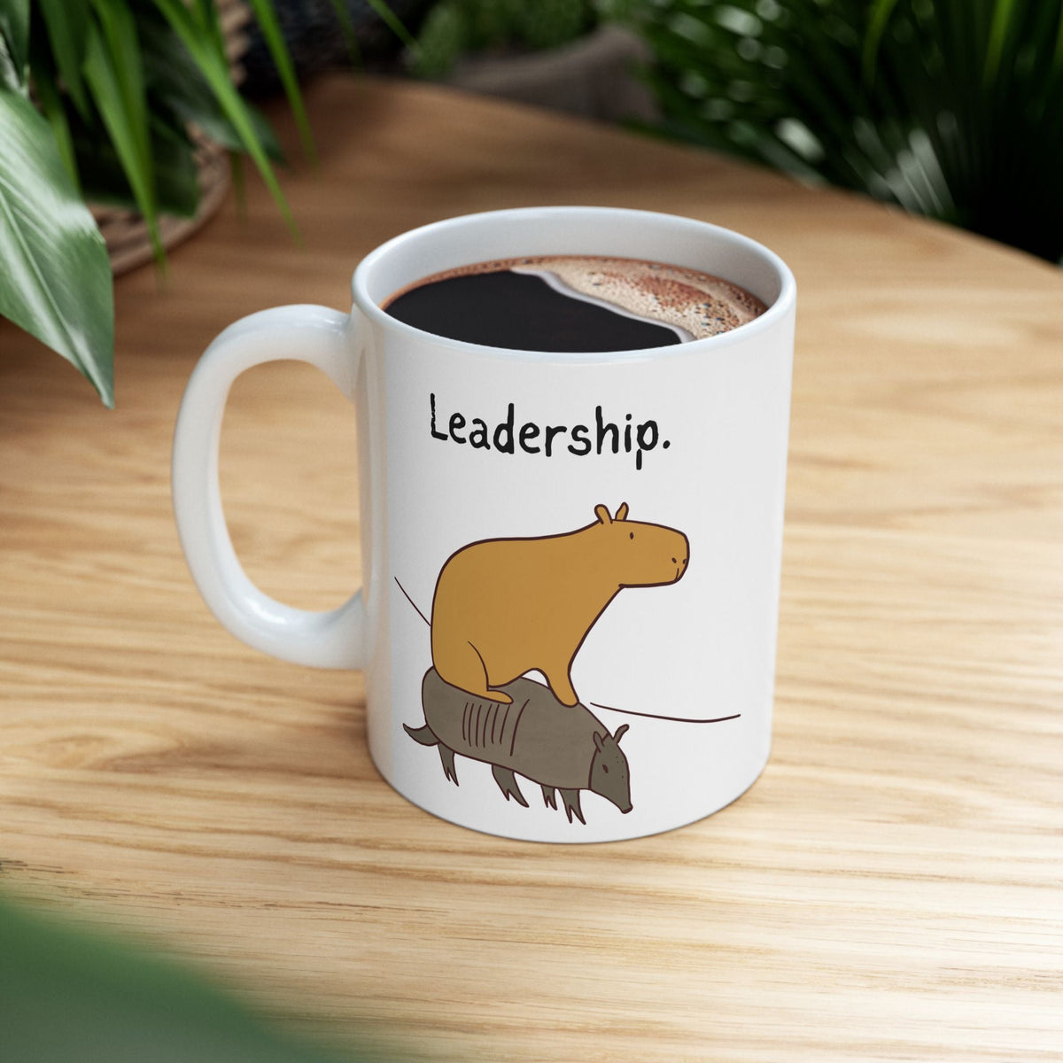 Capy Life Leadership coffee mug featuring a cartoon capybara riding an armadillo on a white ceramic surface