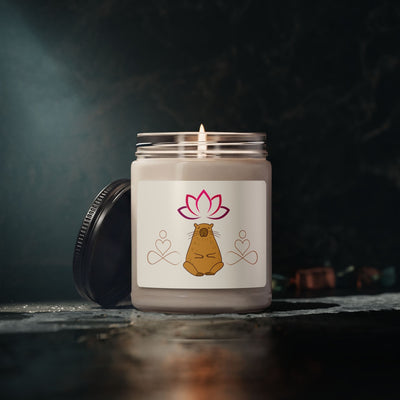 Capy Life scented candle in a glass jar with a meditating capybara and lotus flower label, glowing in dim lighting.