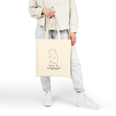 Capy Life natural canvas tote bag featuring a minimalist Gene the Capybara illustration and Always Be Lollygaggin text.