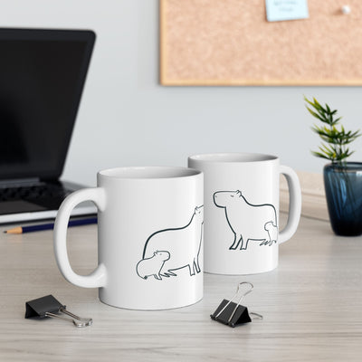 Capy Life white ceramic mug featuring a minimalist black line drawing of a mother capybara and her baby on a desk.