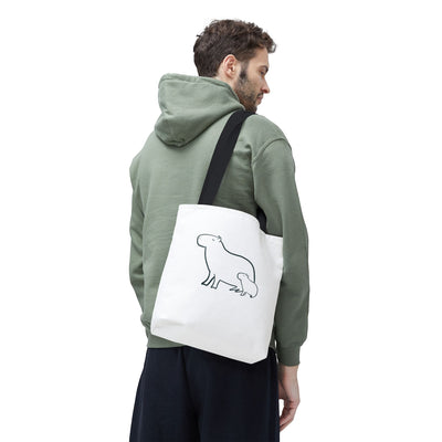 Capy Life minimalist white tote bag featuring a black line art illustration of a capybara mom and baby on a model.