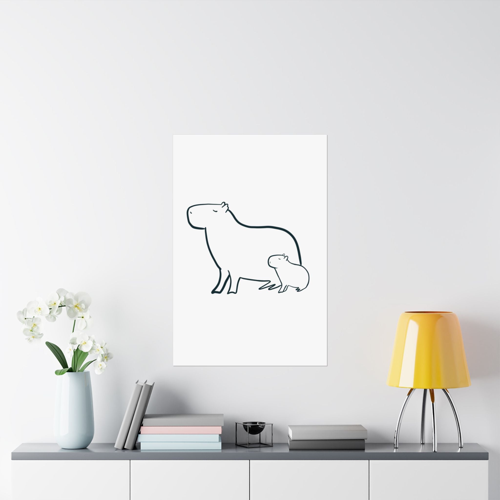 Capy Life minimalist line art print of a mama and baby capybara displayed on a wall above a modern console table.