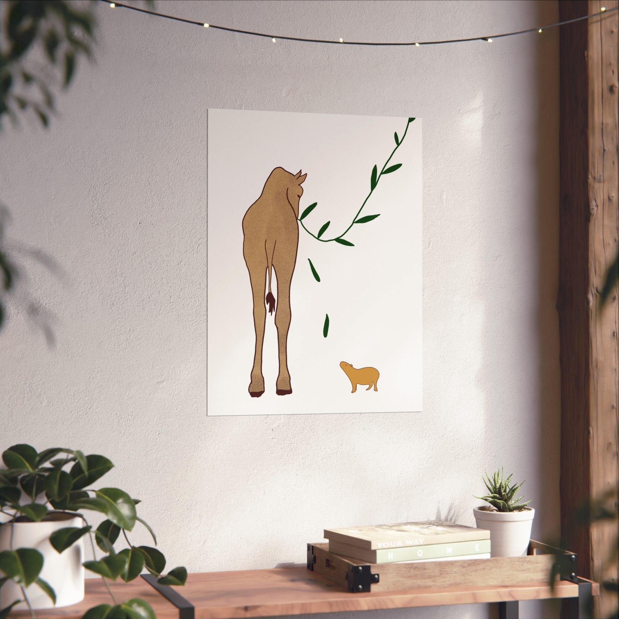 Capy Life minimalist wall art print featuring a giraffe and capybara in neutral tones on a white wall above a wooden shelf