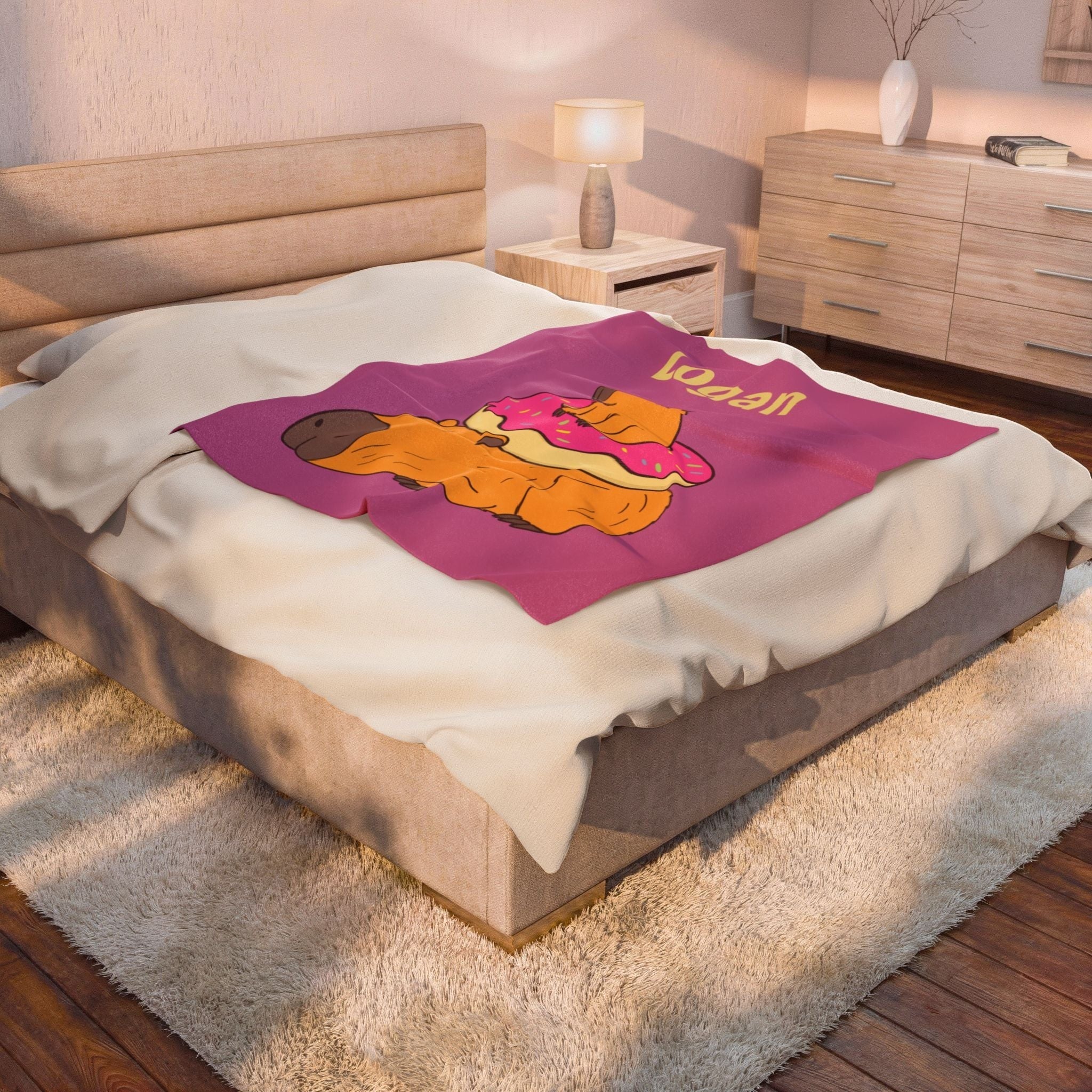 Capy Life personalized kids blanket featuring a cute capybara with a donut on a pink background, draped on a bed.