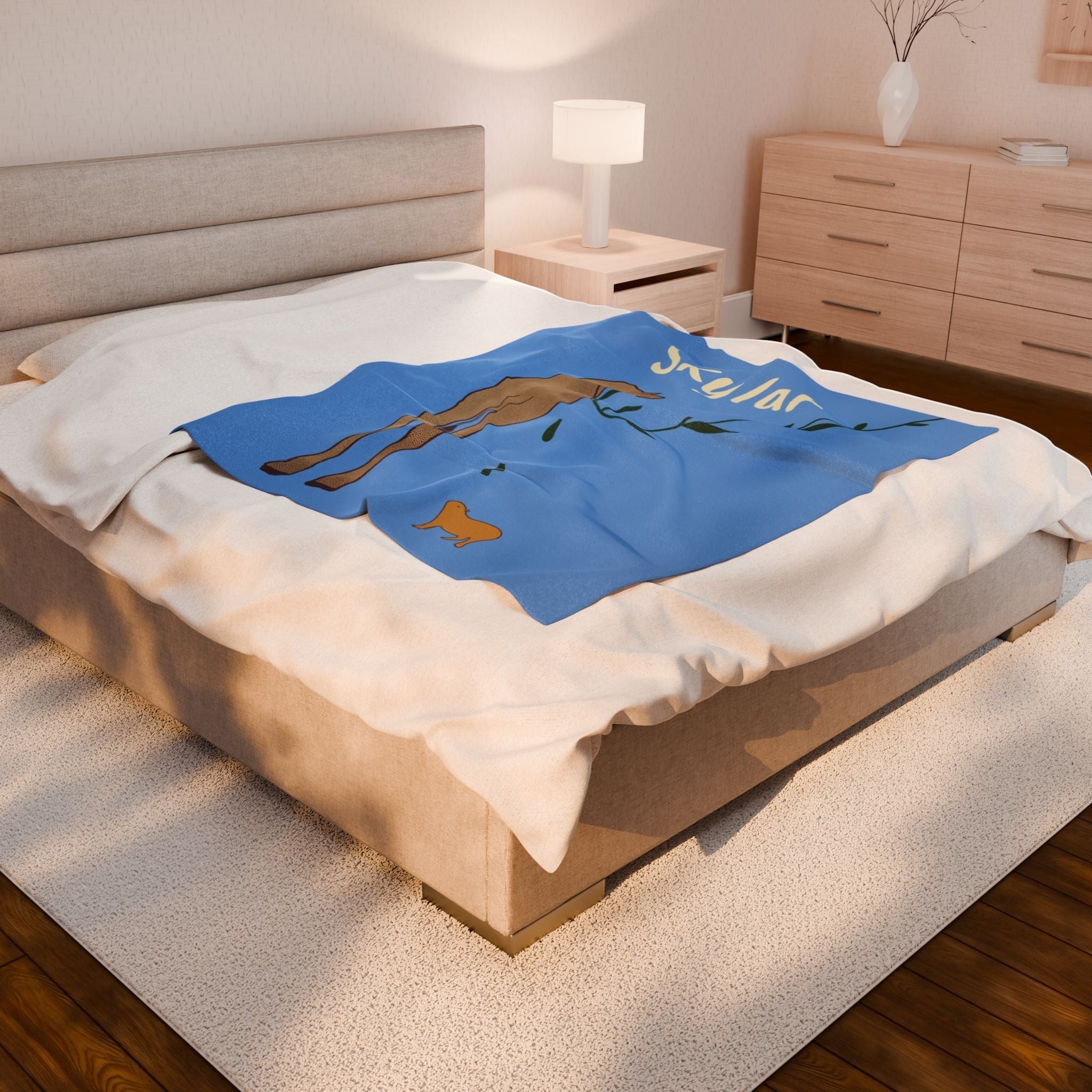 Capy Life personalized blue baby blanket with giraffe and capybara illustration on a bed in a modern nursery.