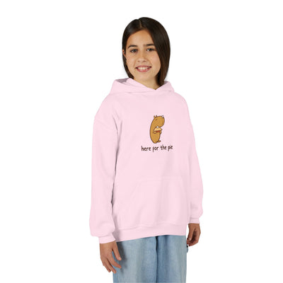 A young girl wearing a light pink Capy Life kids hoodie featuring a cute capybara holding a slice of pie.