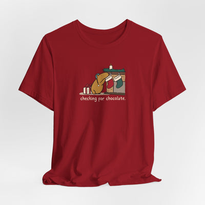 Capy Life red softstyle t-shirt featuring a hand-drawn capybara checking a Christmas stocking for chocolate.