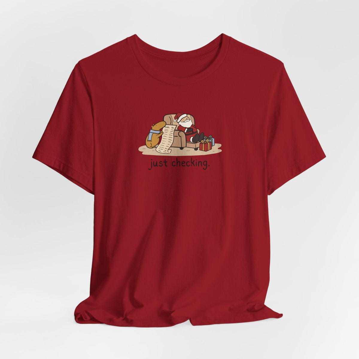 Capy Life red short-sleeve t-shirt featuring a hand-drawn illustration of a capybara checking Santa's naughty list.