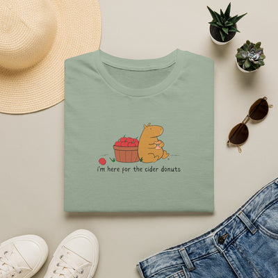 Capy Life sage green softstyle t-shirt featuring a capybara eating a cider donut next to a basket of red apples.