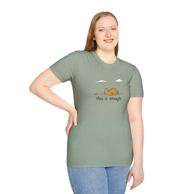 A woman wearing a sage green Capy Life softstyle t-shirt with a capybara graphic and the text This Is Enough.