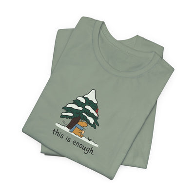 Capy Life sage green graphic t-shirt featuring a capybara in a blue scarf under a snowy evergreen tree.