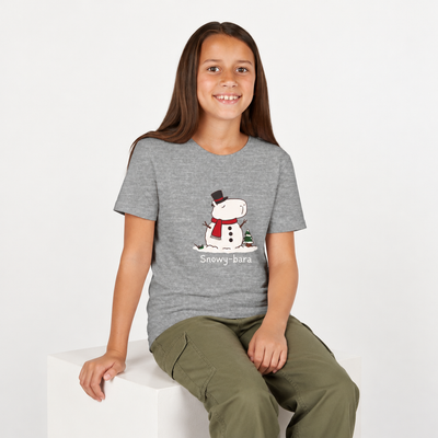 A young girl wearing a Capy Life grey youth t-shirt featuring a cute Snowy-bara snowman capybara graphic.