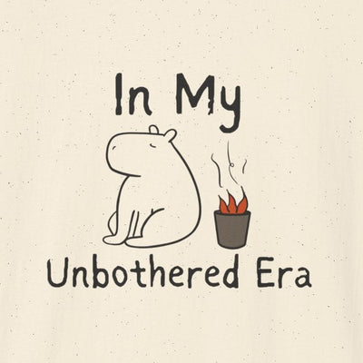 Capy Life graphic t-shirt featuring a hand-drawn calm capybara sitting by a small fire with In My Unbothered Era text