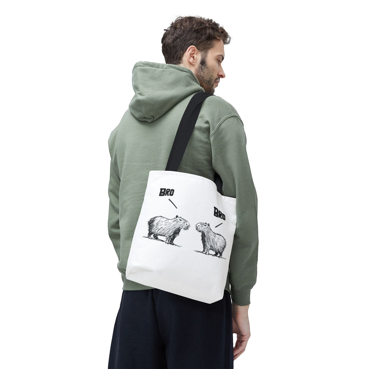 Capy Life white canvas tote bag featuring a funny sketch of two capybaras saying bro, worn over the shoulder.