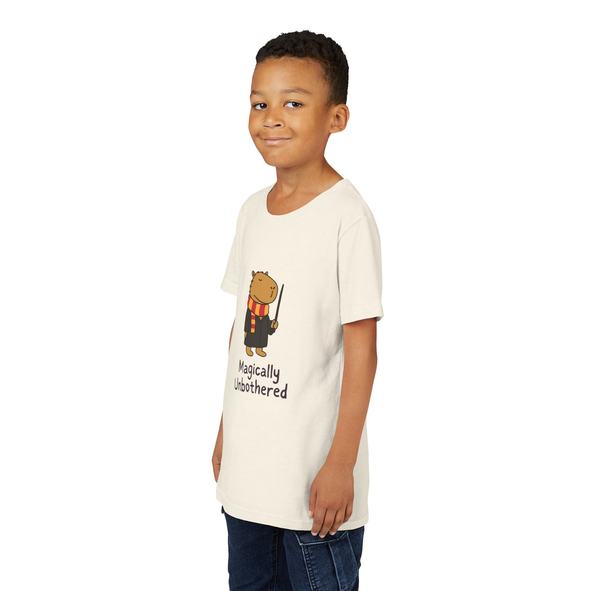Capy Life youth t-shirt featuring a wizard capybara graphic with the text Magically Unbothered on a cream cotton tee